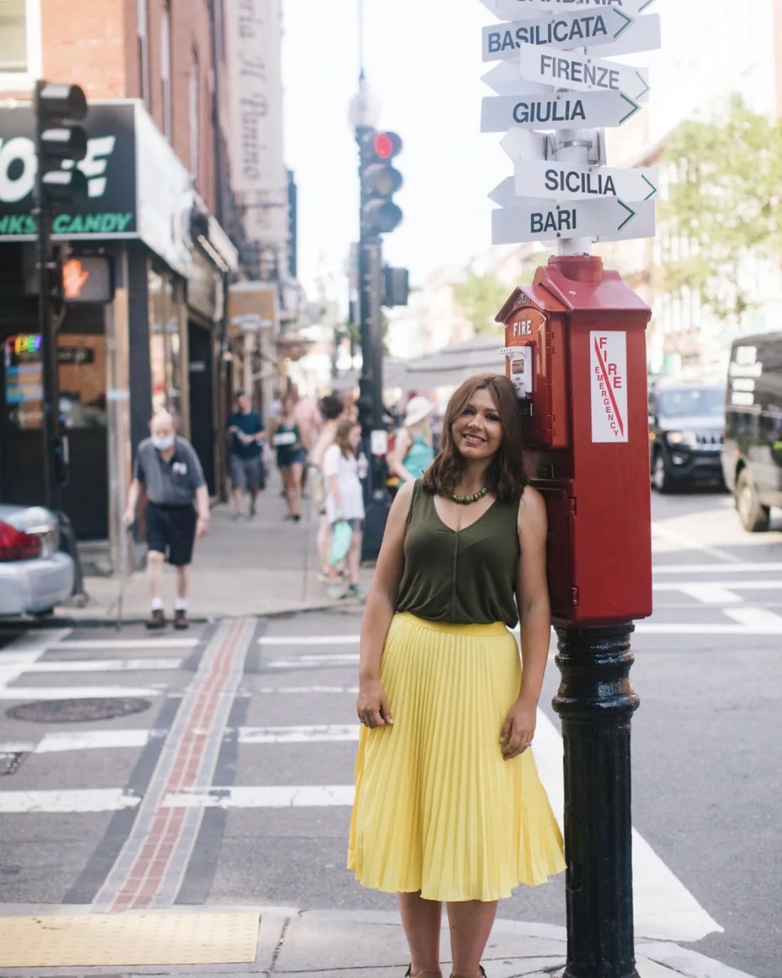 Paula smiling on a North End street corner beneath the Italian-regions signpost